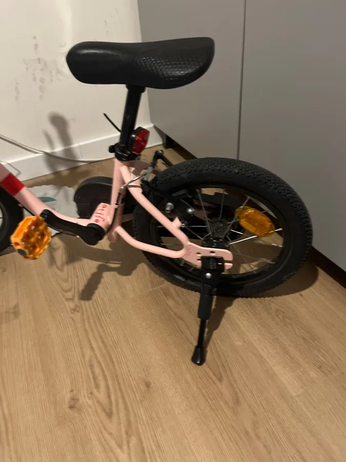 Black side-mount kickstand bolted to the rear frame of a pink 14-inch kids bike, photographed by a verified buyer